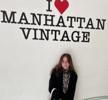 Sarah Gross pictured next to an I hear Manhatten Vintage sign